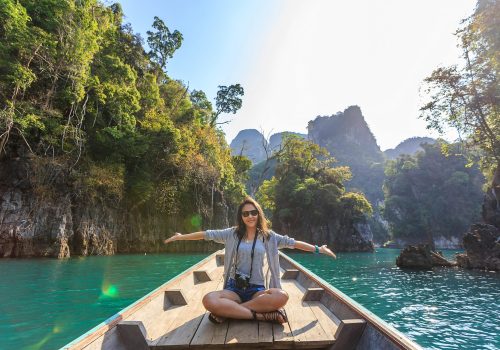 Asian woman relishing a serene boat journey through the lush karst landscape of Thailand's Khlong Sok.